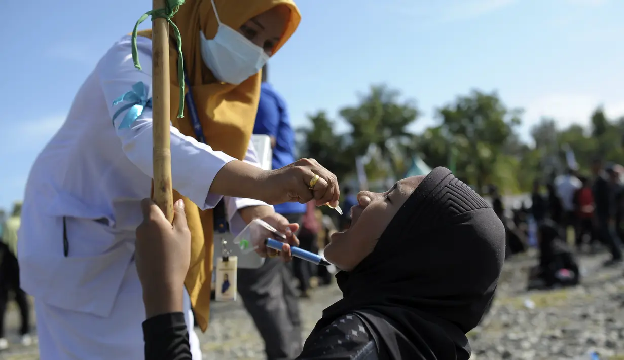 Pekerja medis memberikan imunisasi polio dari petugas medis saat berlangsung vaksinasi massal di Sigli Town Square,  Pidie, Aceh, Senin (28/11/2022).  Menyusul kejadian luar biasa (KLB) polio beberapa pekan lalu di Kabupaten Pidie, pemerintah memberikan imunisasi polio tambahan pada anak usia 0-13 tahun di seluruh wilayah Provinsi Aceh . (AP Photo/Riska Munawarah)