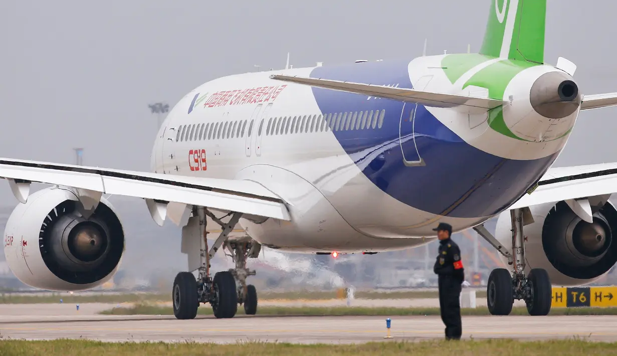Petugas berdiri dekat pesawat penumpang jet C919 jelang penerbangan perdana di Bandara Internasional Pudong, Jumat (5/5). C919 adalah buatan Commercial Aircraft Corporation of China (COMAC) yang merupakan milik pemerintah. (Aly Song/Pool Photo via AP)