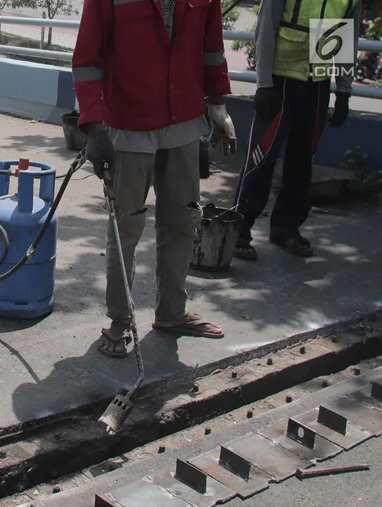 Para pekerja memperbaiki aspal di flyover Kemayoran yang mengalami kerenggangan, Jakarta, Sabtu (5/1). Hal itu disebabkan rusaknya sambungan celah sambungan alias expansion joint. (Merdeka.com/Imam Buhori)