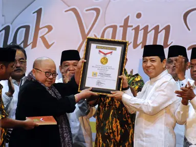 Ketua Umum Partai Golkar, Setya Novanto (kedua kanan) mengangkat penghargaan dari MURI jelang buka puasa AMPG bersama ribuan anak yatim piatu di Jakarta, Sabtu (18/6). Acara diikuti sekitar 26 ribu anak yatim piatu. (Liputan6.com/Helmi Fithriansyah)