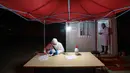 Para pekerja berpakaian pelindung duduk di luar hotel yang digunakan dalam isolasi medis virus corona di Wuhan, Provinsi Hubei, China, Senin (3/2/2020). Dokter pengungkap virus corona, dr Li Wenliang, sempat dituduh menyebarkan informasi palsu. (Chinatopix via AP)