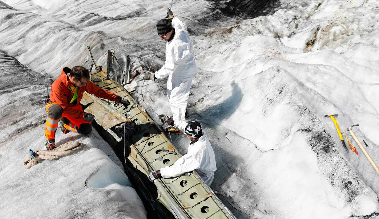 Anggota tentara Swiss memeriksa bagian pesawat tempur Perang Dunia II milik AS saat ditemukan di Gauli Glacier, di Bernese Alps, Swiss (17/9). Pesawat Perang Dunia II C-53 Skytrooper Dakota tersebut jatuh tahun 1946. (Peter Klaunzer/Keystone via AP)