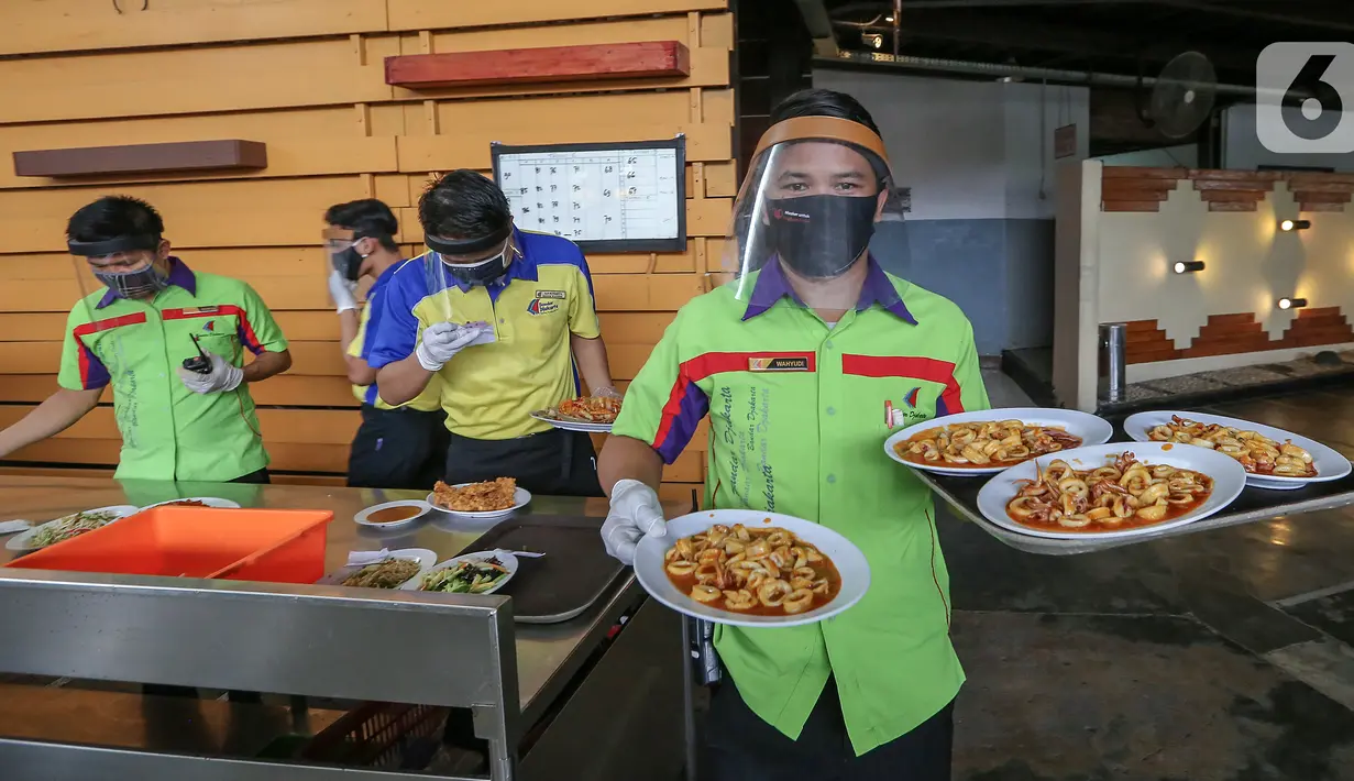 Pramusaji lengkap dengan Alat Pelindung Diri (APD) berupa face shield, sarung tangan dan masker membawa makanan untuk konsumen di Restoran Bandar Djakarta, Alam Sutera, Tangerang Selatan, Rabu (10/6/2020). Menuju new normal restoran tetap menerapkan protokol kesehatan. (Liputan6.com/Fery Pradolo)