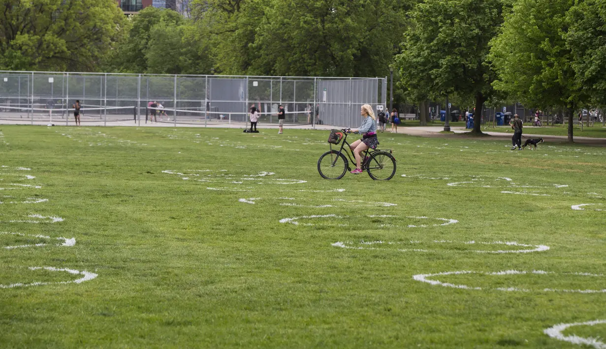 Pesepeda melewati lingkaran putih di Taman Trinity Bellwoods, Toronto, Kanada, Kamis (28/5/2020). Taman Trinity Bellwoods digambari lingkaran-lingkaran putih sebagai proyek uji coba untuk mendorong warga melakukan jaga jarak fisik (physical distancing) selama pandemi COVID-19. (Xinhua/Zou Zheng)