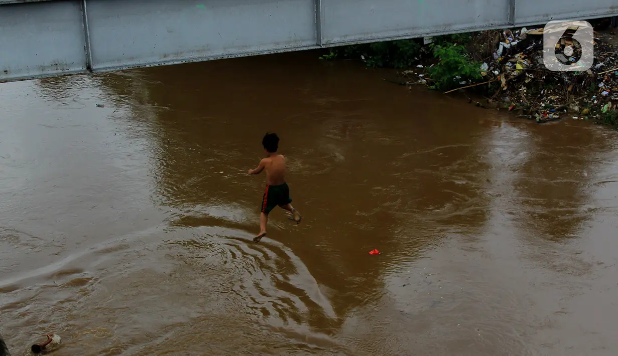 Seorang anak nekat melompat dari jembatan ke Kali Ciliwung Kalibata, Jakarta, Selasa (25/2/2020). Kali Ciliwung meluap usai hujan deras mengguyur Jakarta dan sekitarnya pada kemarin malam. (merdeka.com/magang/Muhammad Fayyadh)