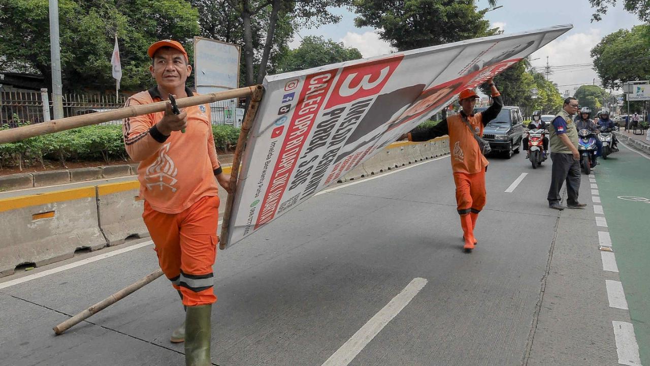 Petugas Penanganan Prasarana dan Sarana UMum (PPSU) menertibkan alat peraga kampanye (APK) di kawasan Jati Padang, Jakarta, Minggu (11/2/2024). Berbagai APK, mulai dari bendera, spanduk, hingga baliho, yang bertebaran dan menyebabkan pemandangan kota terl