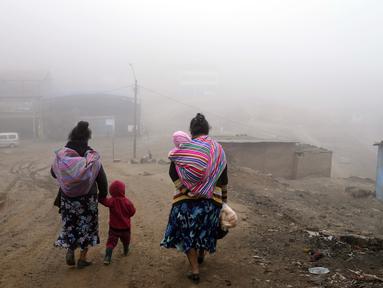Warga berjalan melalui kabut dingin dan tebal pada hari resmi pertama musim dingin, di lingkungan Ticlio Chico di pinggiran Lima, Peru, Selasa (21/6/2022). Suhu di ibu kota adalah yang terendah dalam 25 tahun, menurut National Layanan Meteorologi dan Hidrologi Peru. (AP Photo/Martin Mejia)