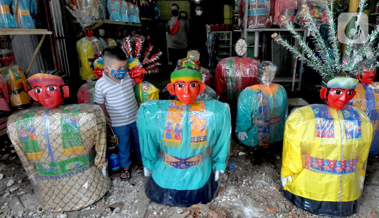 Seorang anak melihat ondel-ondel di Rumah Produksi Ondel-Ondel Jakarta, Setu Babakan, Jakarta Selatan, Minggu (19/9/2021). Ondel-ondel dijual dengan harga Rp 35 ribu hingga Rp 7 juta per pasang. (merdeka.com/Arie Basuki)