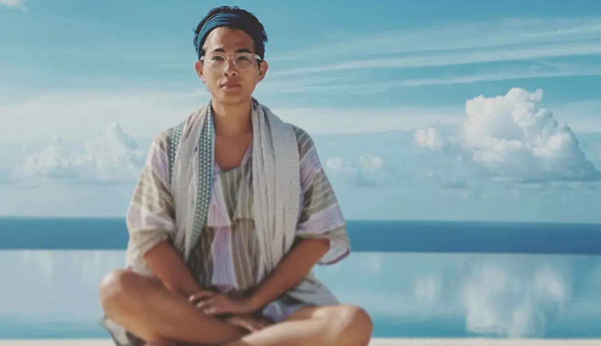 Desainer yang dikenal dengan rancangan bernapaskan Indonesia ini juga terlihat memakai outfit etnik dengan motif bergaris yang modern. Jangan lupa aksesori bandana untuk menahan rambut dari tiupan angin pantai. (Foto: Instagram/oscarlawalata)