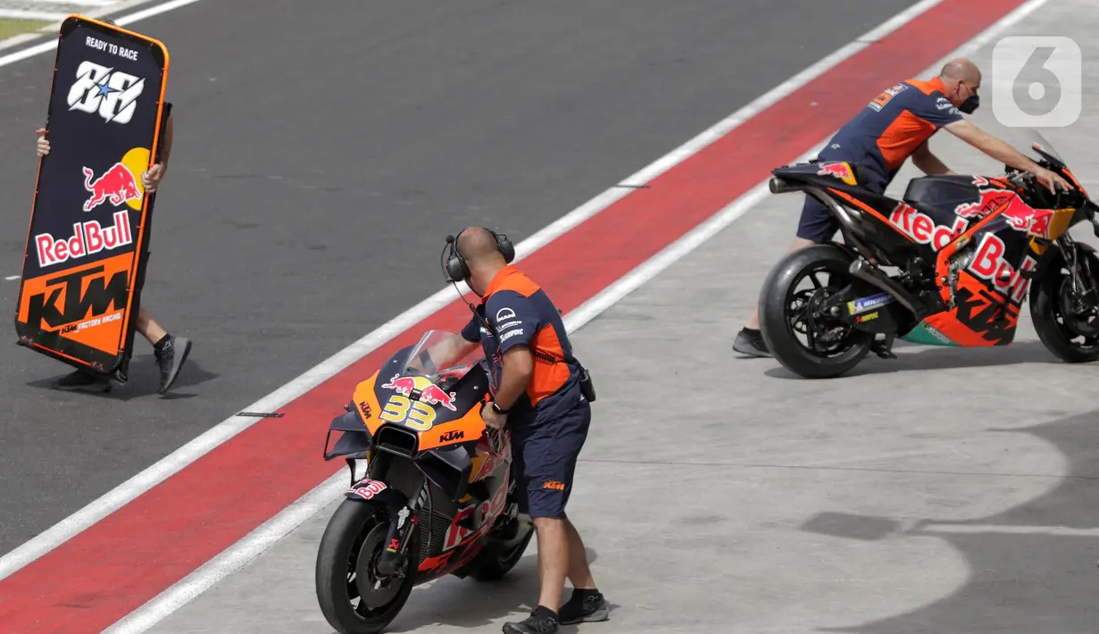 Teknisi Red Bull KTM Factory Racing mendorong motor tunggangan Miguel Oliveira saat sesi Warm Up MotoGP di Pertamina Mandalika International Street Sirkuit, Nusa Tenggara Barat, Minggu (20/3/2022). (Liputan6.com/Helmi Fithriansyah)