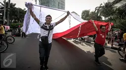 Peserta membentangkan bendera merah putih raksasa pada Karnaval Cinta Budaya NKRI di MH Thamrin, Jakarta, Minggu (20/11). Karnaval ini bertujuan merawat dan menyiram perdamaian, toleransi, harmoni dan persaudaraan kebangsaan. (Liputan6.com/Faizal Fanani)
