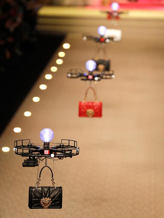 Pesawat tanpa awak (drone) keluar dari belakang panggung sembari terbang membawa koleksi tas musim gugur Dolce & Gabbana pada Milan Fashion Week 2018, Minggu (25/). Aksi yang tak biasa ini membuat para tamu terkejut. (Miguel MEDINA/AFP)