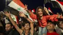 Pendukung Presiden Suriah Bashar Assad mengibarkan bendera nasional saat mereka merayakan kemenangannya di Omayyad Square, di Damaskus, Kamis (27/5/2021). Bashar al-Assad terpilih kembali untuk masa jabatan keempat sebagai presiden Suriah yang dilanda perang. (AP Photo/Hassan Ammar)