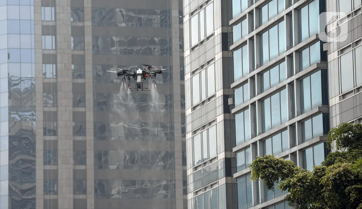 Drone menyemprotkan cairan disinfektan di Jalan Bursa Efek menuju Patung  Pemuda, Jakarta, Jumat (27/3/2020). Penyemprotan dilakukan untuk mencegah penyebaran virus corona COVID-19. (merdeka.com/Imam Buhori)