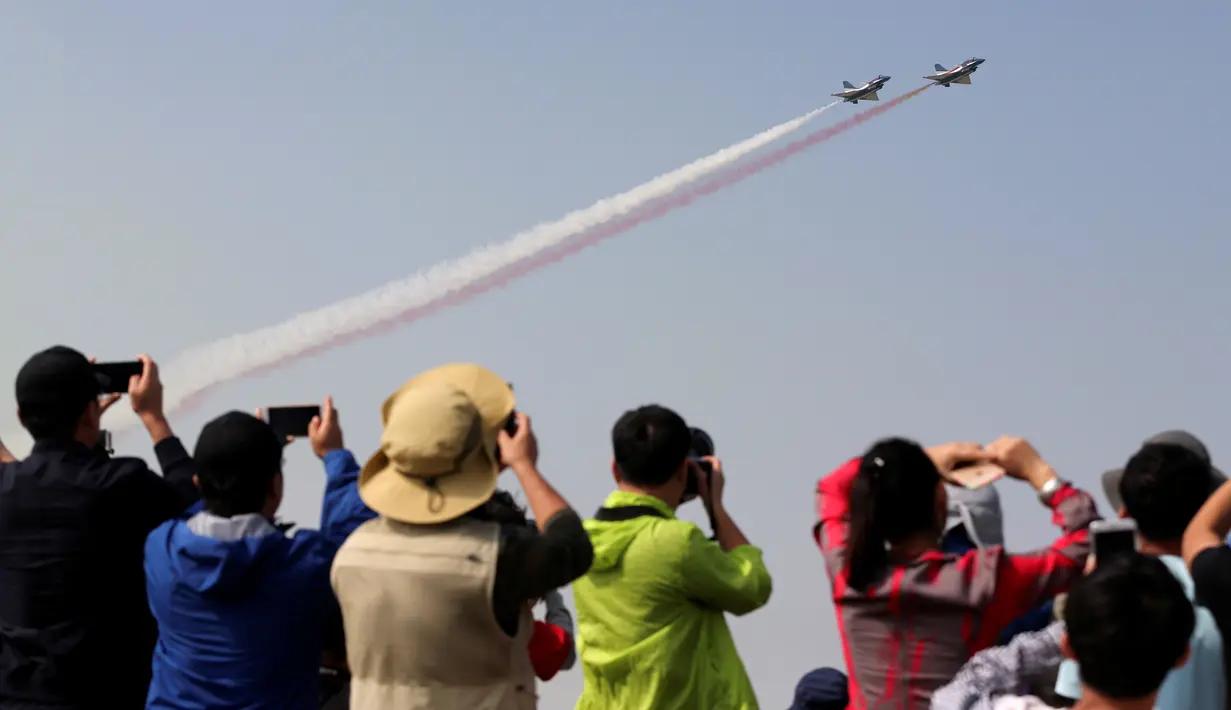 Pengunjung mengambil gambar jet tempur yang sedang beraksi di acara Zhuhai Air Show, di Provinsi Guangdong, Tiongkok, Selasa (1/11). Pertunjukan udara ini merupakan upaya Tiongkok untuk memodernisasi kemampuan militernya. (REUTERS/ China Daily)
