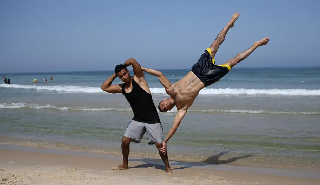 Anggota street workout Palestina, Bar Palestine, beraksi di pantai kota Gaza, Palestina. (7/8/2015). Street workout adalah latihan olahraga yang memanfaatkan fasilitas seadanya. (AFP Photo/Mohammed Abed)