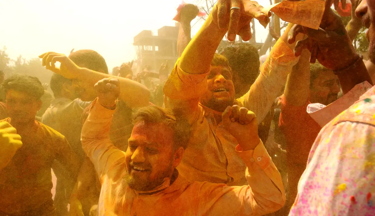 Umat Hindu menari saat bubuk berwarna dilemparkan ke arah mereka di Ladali atau kuil Radha selama festival Lathmar holi di Barsana, India, Selasa (23/3/2021). Perayaan Lathmar Holi berlangsung dari 23 Maret hingga 29 Maret tahun ini. (AP Photo)