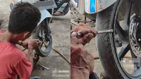 Montir melepas ban motor (TikTok/@anakdesa179)