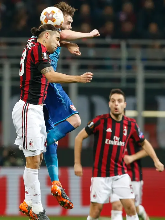 Pemain AC Milan Ricardo Rodriguez berebut bola di udara dengan Jack Wilshere saat pertandingan Liga Europa leg pertama di stadion San Siro Milan, Italia (8/3). (AP Photo / Antonio Calanni)
