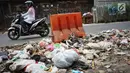 Pengendara melintasi tumpukan sampah rumah tangga di Jalan Raya Tanah Baru kawasan Depok, Jawa Barat, Rabu (15/5/2019). Kurangnya tempat penampungan membuat warga terpaksa membuang sampah di lokasi tersebut, meskipun menimbulkan bau tidak sedap serta mengotori jalan. (Liputan6.com/Immanuel Antonius)