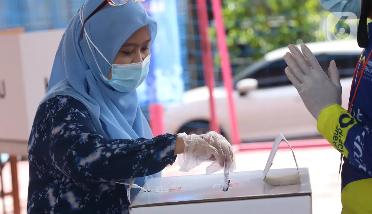 Pemiilih mengenakan sarung tangan plastik saat menggunakan hak suaranya dalam Pilkada Tangerang Selatan di TPS 23 Pondok Jagung Timur, Rabu (9/12/2020). Menggunakan masker hingga memakai sarung tangan plastik menjadi hal wajib saat melakukan pencoblosan di Pilkada 2020. (Liputan6.com/Angga Yuniar)
