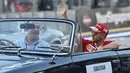 Pembalap Formula 1 Ferrari asal Jerman, Sebastian Vettel menyapa pengemar saat di mobil Mercedes-Benz klasik saat mengikuti parade jelang Grand Prix Formula 1 Malaysia di Sirkuit Internasional Sepang, Malaysia, (2/10). (AFP PHOTO/Anthony Wallace)
