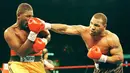 Mike Tyson adalah petinju paling kontroversial dan juga legenda yang memiliki pukulan keras. Dari 50 Kemenangan, 44 diantaranya menang KO. Foto ini saat Mike Tyson (kanan) melawan Buster Mathis Jr. di Spectrum, Philadelphia. (AFP/Timothy A. Clary) 