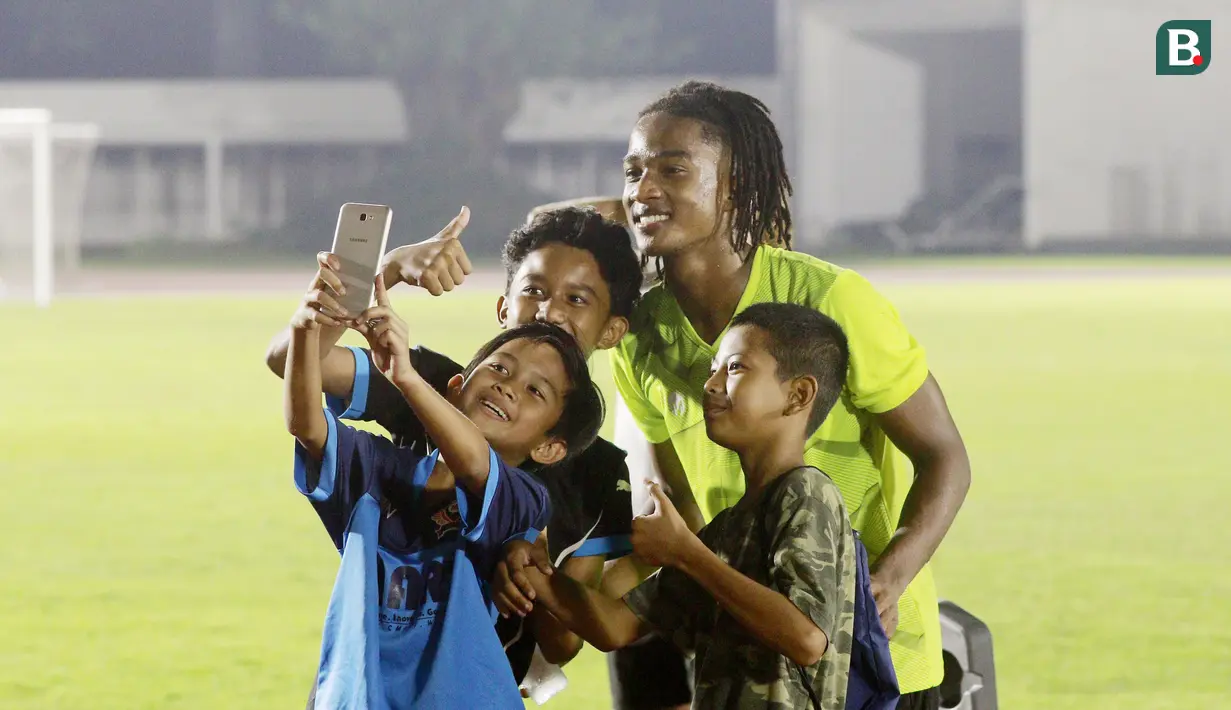 Fans cilik foto bersama dengan pemain Timnas  Indonesia U-19, Ronaldo Kwateh, usai melakukan latihan jelang Piala AFF U-19 2022 di Stadion Madya, Jakarta, Selasa (21/6/2022). (Bola.com/M Iqbal Ichsan)