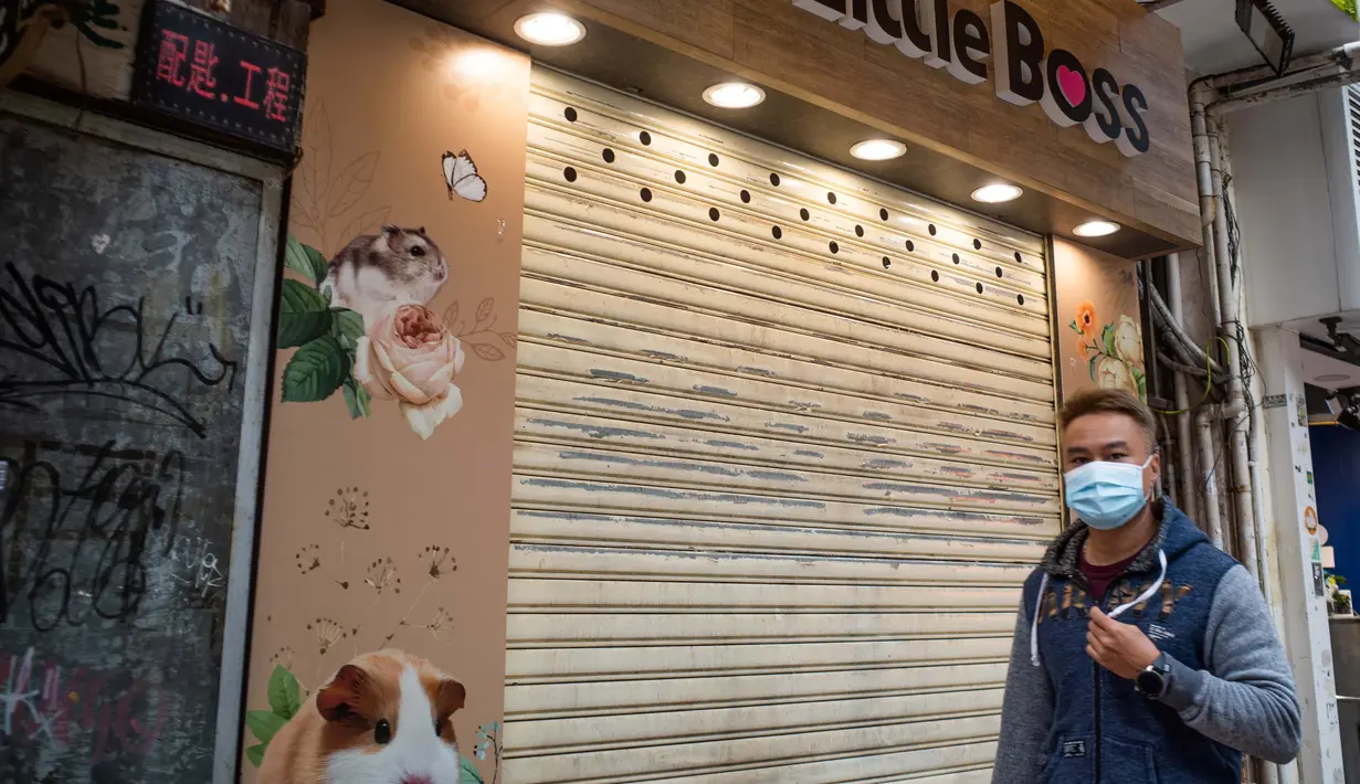 Seseorang melewati toko hewan peliharaan tempat seorang karyawan dan pelanggan dinyatakan positif Covid-19 setelah menangani hamster di Causeway Bay, Hong Kong pada 18 Januari 2022,  memicu rencana pemusnahan lebih dari 1.000 hewan kecil usai beberapa hamster dinyatakan positif. (Bertha WANG/AFP)