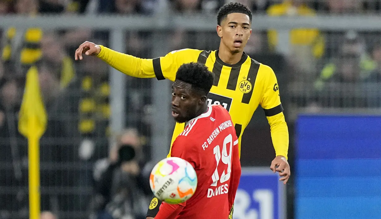Bek Bayern Munchen Alphonso Davies dan gelandang Borussia Dortmund Jude Bellingham menatap bola dalam laga lanjutan Bundesliga, kasta tertinggi Liga Jerman, musim 2022-2023, di Signal-Iduna Park, Sabtu (9/10/2022). Tambahan satu poin membuat Bayern tertahan di posisi ketiga klasemen dengan 16 poin, selisih satu angka dari Union Berlin di puncak. (AP Photo/Martin Meissner)