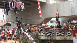 Warga bermain lomba jalan di atas batang pohon pinang di sekitar Kalimalang, Jakarta, Sabtu (17/8/2019). Beragam lomba permainan digelar warga untuk menyemarakkan HUT ke-74 Republik Indonesia. (Liputan6.com/Helmi Fithriansyah)