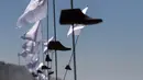 Sejumlah cetakan kayu sepatu dengan bendera putih yang merupakan seni instalasi di pajang di Playas de Tijuana, Meksiko (7/10). Seni instalasi yang bercerita tentang migran Meksiko ini adalah karya seniman Betsabee Romero. (AFP Photo/Guillermo Arias)