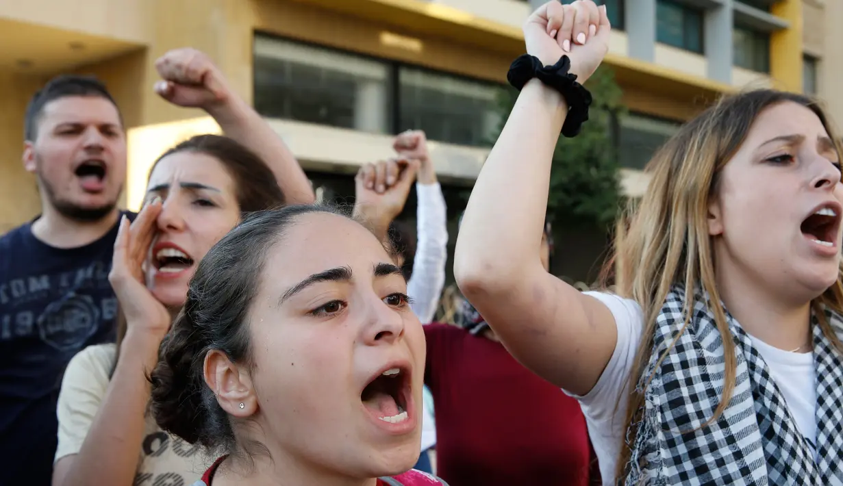 Pengunjuk rasa meneriakkan "Revolusi" setelah PM Lebanon Saad Hariri mengumumkan pengunduran dirinya, di depan istana pemerintahan di Beirut, Selasa (29/10/2019). Pengunduran diri itu buntut dari protes besar-besaran yang ditujukan kepada elite penguasa Lebanon baru-baru ini. (AP/Bilal Hussein)