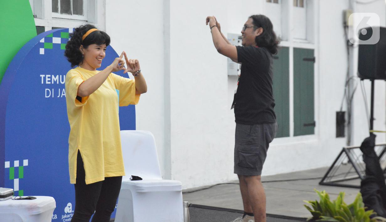 Teman tuli mengajak pengunjung untuk tampil menggunakan bahasa isyarat di Festival #IniJakarta2022, Kota Tua, Jakarta, Minggu (18/9/2022). Komunitas Tuli SilangHub mengajak pengunjung ngobrol bareng dan belajar bahasa isyarat dengan teman tuli.(Liputan6.com/Magang/Aida Nuralifa)