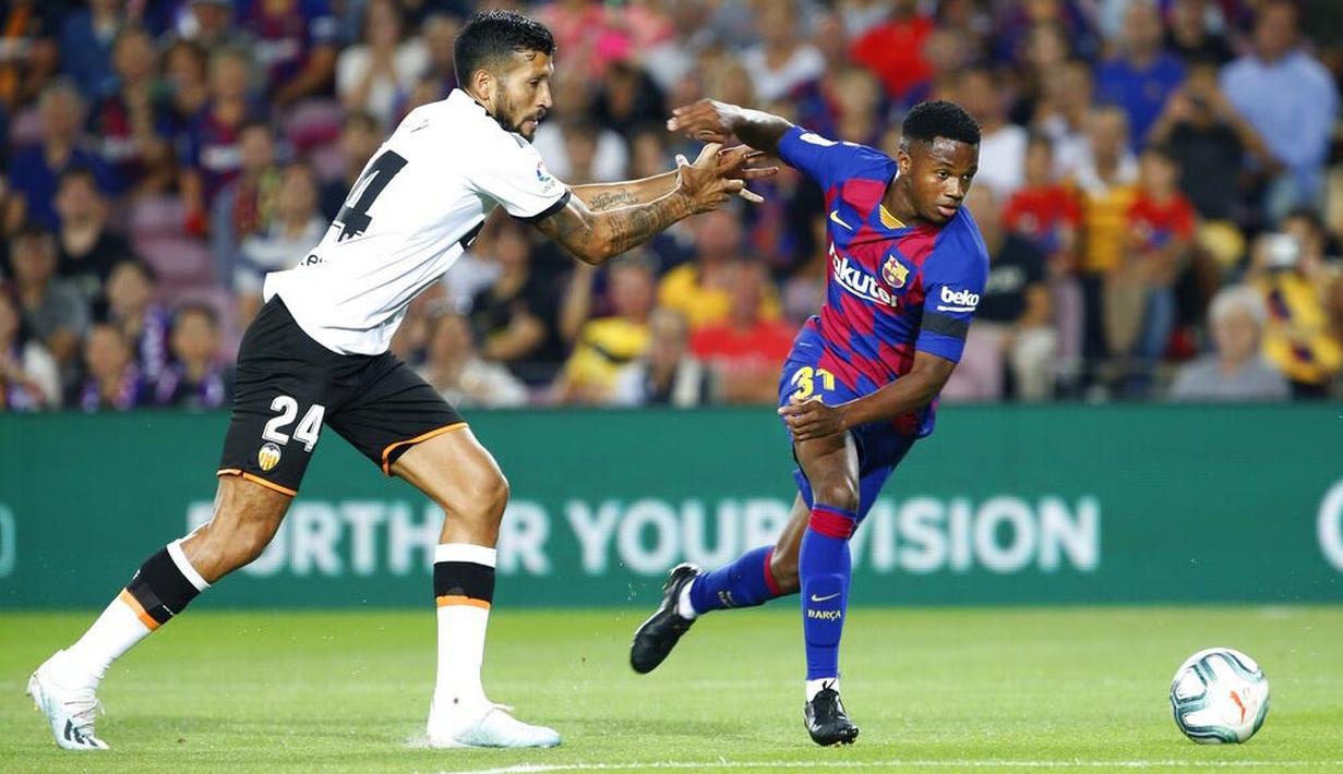 Penyerang Barcelona, Ansu Fati, berusaha melewati bek Valencia, Ezequiel Garay, pada laga La Liga di Stadion Camp Nou, Sabtu (14/9). Barcelona menang 5-2 atas Valencia. (AP/Joan Monfort)