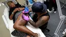 Seorang wanita saat dibuatkan tato dibagian pahanya oleh seniman dalam acara Bali Tattoo Expo 2017 di pulau resor Indonesia, Denpasar, Bali (12/5). Acara ini digelar selama 3 hari, mulai (12/5/2017) sampai (14/5/2017). (AFP Photo/Sonny Tumbelaka)