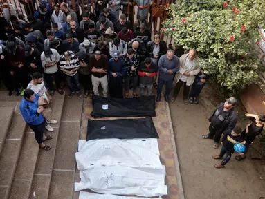 Warga Palestina berdoa dekat jenazah kerabat mereka yang tewas dalam pemboman Israel di Jalur Gaza, di luar kamar mayat di Khan Younis, Rabu (27/12/2023). (AP Photo/Mohammed Dahman)