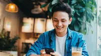 Seorang pria menggunakan smartphone di cafe. (havucvp/depositphotos.com)