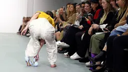 Seorang model membetulkan sepatunya saat memperagakan busana rancangan Emilio De la Morena pada London Fashion Week 2017 di Inggris, Selasa (20/9).  Meski sepatunya terlepas, model ini percaya diri berjalan dengan sebelah alas kaki. (REUTERS/Neil Hall)
