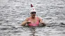 Seorang anggota klub renang "Berliner Seehunde" (Berlin Seals) berendam di Danau Orankesee, Berlin, Minggu (25/12). Kegiatan yang sudah menjadi tradisi ini merupakan bagian dari perayaan tradisional Natal bagi warga Berlin. (Tobias SCHWARZ / AFP)