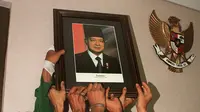 Mahasiswa mencopot foto Presiden Soeharto di gedung parlemen Senayan, Jakarta pada 21 Mei 1998. Soeharto yang telah telah menjadi presiden Indonesia selama 32 tahun mundur setelah runtuhnya dukungan untuk dirinya. KEMAL JUFRI/AFP)