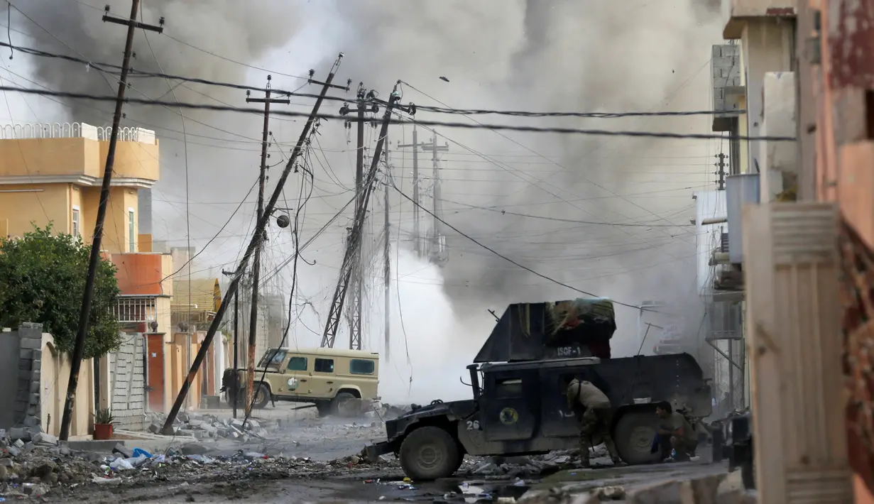 Seorang tentara pasukan khusus Irak berlindung di balik kendaraan militer humvee menyusul serangan bom mobil bunuh diri yang dilakukan militan ISIS di kota Tahrir, Irak, 17 November 2016. (REUTERS/Goran Tomasevic)