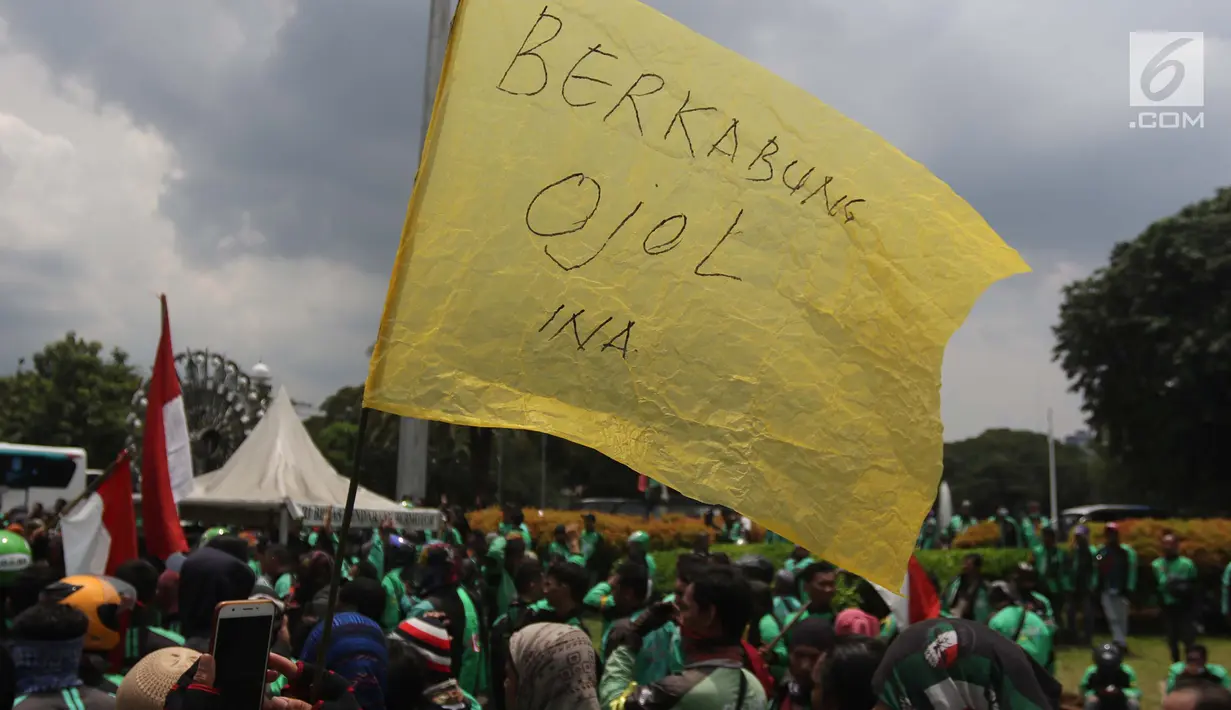 Pengemudi ojek online membawa bendera kuning saat melakukan aksi di seberang Istana Merdeka, Jakarta, Selasa (27/3). Dalam aksinya mereka menuntut pemerintah melakukan penetapan tarif standar dengan nilai yang wajar. (Liputan6.com/Arya Manggala)