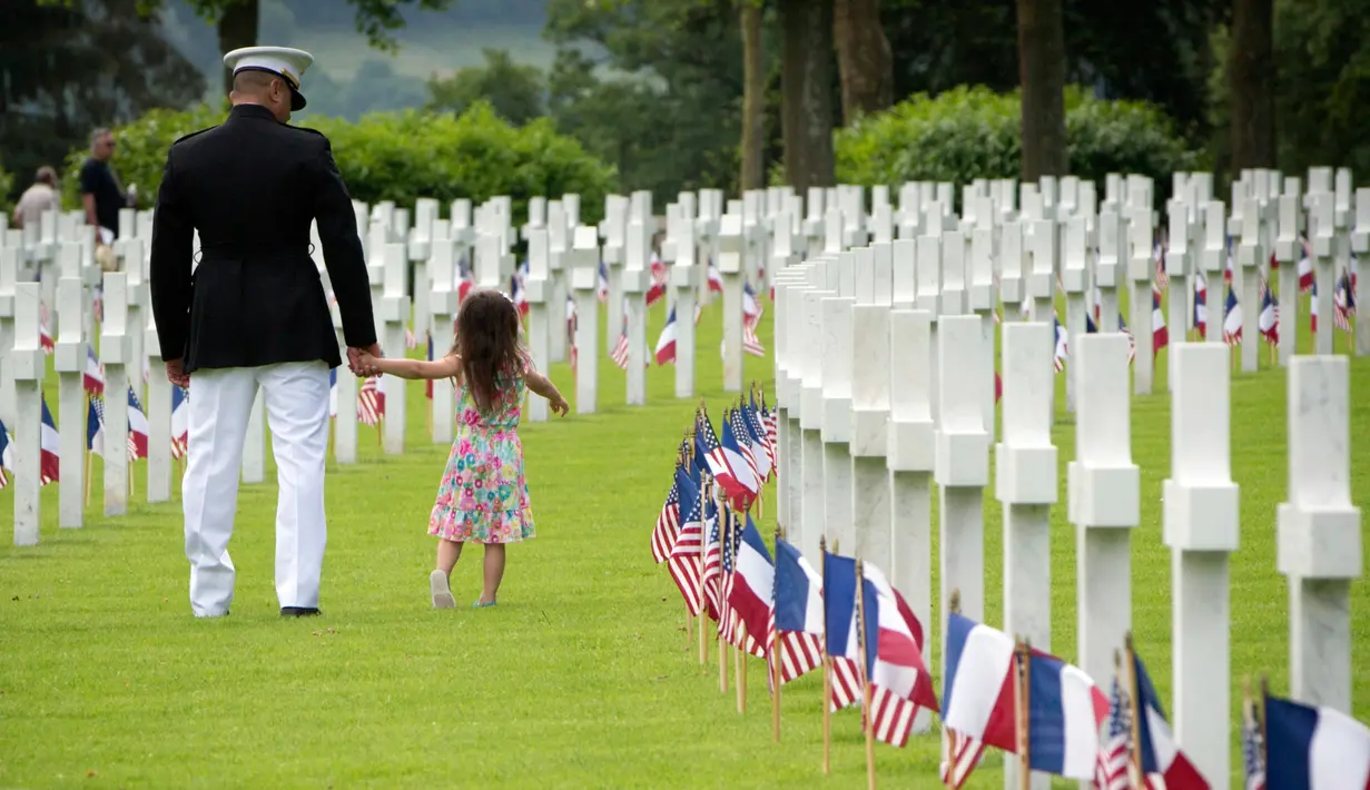 Anggota Marinir AS membawa anaknya saat mengikuti upacara Hari Peringatan Perang Dunia I di Pemakaman Amerika Aisne-Marne di Belleau, Prancis (27/5). (AP Photo / Virginia Mayo)