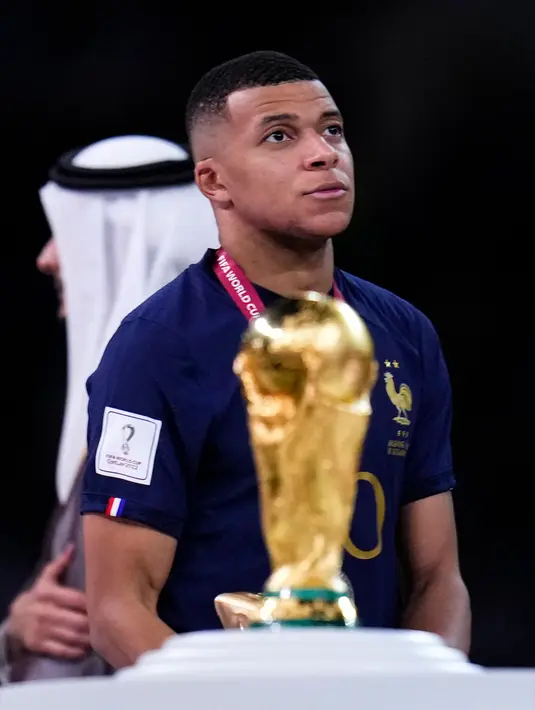 Ekspresi pemain Prancis Kylian Mbappe saat berjalan melewati trofi Piala Dunia 2022 usai melawan Argentina pada pertandingan final di Stadion Lusail, Lusail, Qatar, 18 Desember 2022. Argentina menang 4-2 dalam adu penalti melawan Prancis setelah pertandingan berakhir imbang 3 -3. (AP Photo/Manu Fernandez)