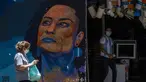 Seorang wanita melewati lukisan perkotaan yang menampilkan gambar mendiang anggota dewan Marielle Franco, yang dibuat seniman Caze dan produser Pedro Rojao, di Rio de Janeiro, 17 November 2021. Brasil menyambut Hari Kesadaran Kulit Hitam yang diperingati setiap 20 November. (AP Photo/Bruna Prado)