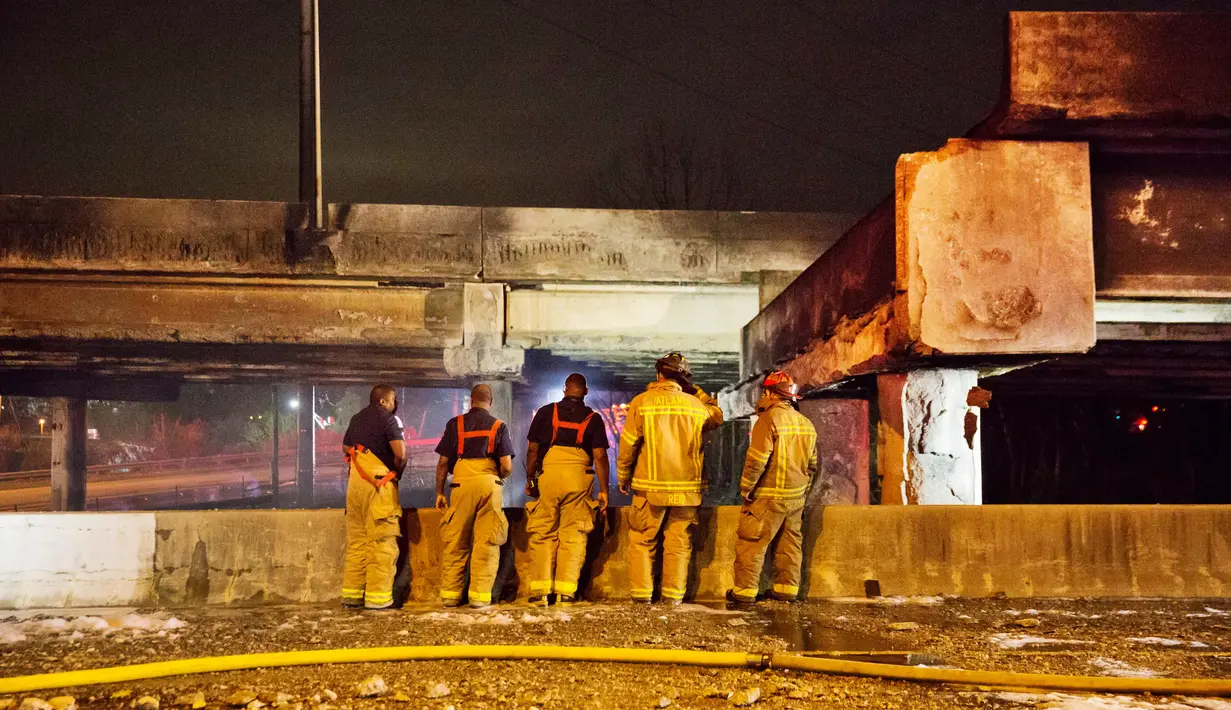 Petugas damkar seusai memadamkan kebakaran yang meruntuhkan jembatan layang di jalur Interstate 85 di Atlanta, AS, Kamis (30/3). Jalan tol tersibuk di AS itu runtuh satu jam setelah kebakaran hebat terjadi di bawah jembatan. (AP Photo/David Goldman)