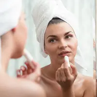 Ilustrasi mengoleskan lipbalm atau pelembap bibir. (iStockphoto)