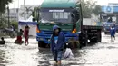 Warga berjalan melintasi genangan banjir rob yang menggenangi kawasan Pelabuhan Nizam Zachman, Muara Baru,  Jakarta, Jumat (5/6/2020). Banjir rob di Pelabuhan Muara Baru tersebut terjadi akibat cuaca ekstrem serta pasang air laut. (Liputan6.com/Helmi Fithriansyah)
