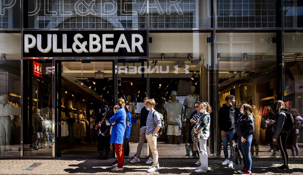 Pelanggan menunggu dalam antrean di depan toko pakaian Pull & Bear yang dibuka kembali di shopping street di Amsterdam, Rabu (28/4/2021). Belanda mulai melonggarkan pembatasan ketat terkait Covid-19, mengakhiri jam malam dan mengizinkan kafe untuk buka di luar ruangan. (REMKO DE WAAL/ANP/AFP)